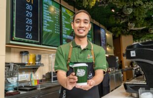 A Cafe Amazon barista showing off a cup of coffee.