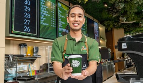 A Cafe Amazon barista showing off a cup of coffee.